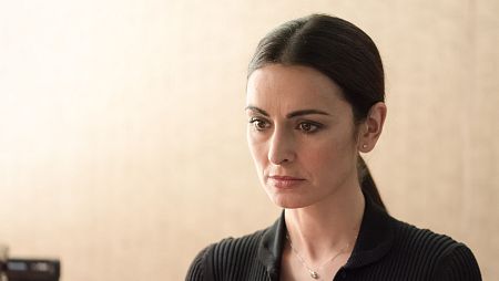 Miriam Sánchez, con gesto serio, mira hacia abajo con una blusa negra y una fina cadena de plata.