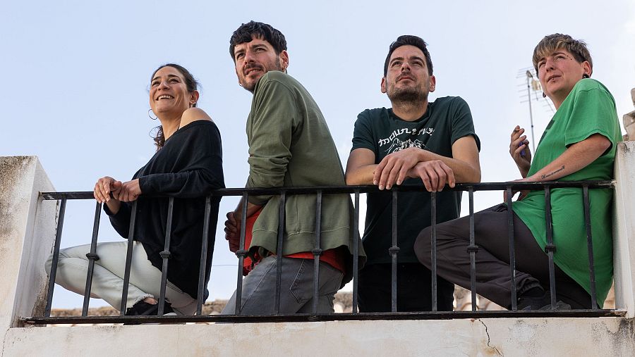 Cuatro personas miran al cielo desde una azotea, dos de ellas cogidas de la mano.