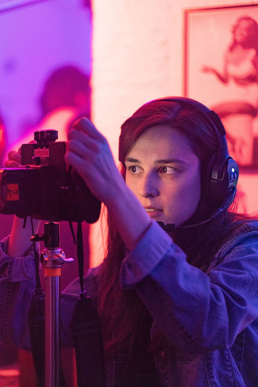 Sandra Romero graba con una cámara en un set con iluminación rosa y violeta.