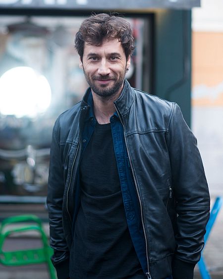 Quique San Francisco, con chaqueta de cuero negra y camisa azul, posa con una leve sonrisa.