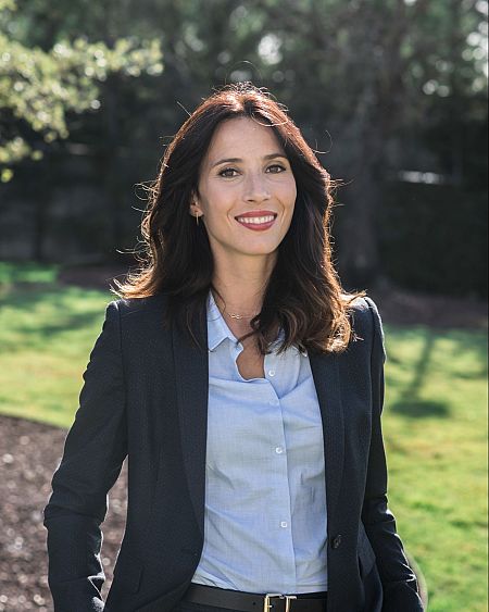Lola Dueñas, actriz española, posa con una americana oscura y camisa azul claro en una imagen promocional.
