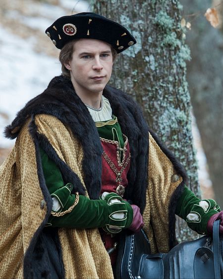 Hombre caracterizado como el emperador Carlos V, con vestimenta de época, posando junto a una silla de montar.