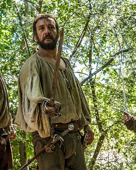 Aitor Luna como Hernán Cortés, espada en mano, en una escena con vestuario de época en un bosque.