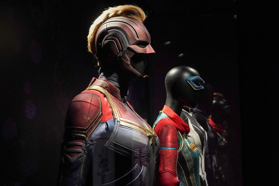 Exhibición de trajes de la película 'Capitana Marvel', incluyendo el de la protagonista y otro con máscara y detalles en rojo y verde.