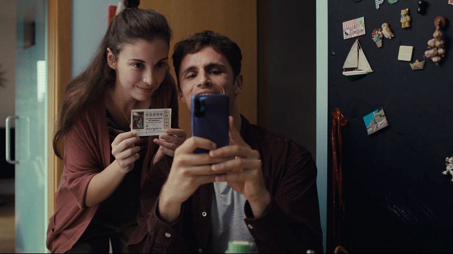 Pareja comparte un décimo de Lotería de Navidad haciendo una foto con el móvil.