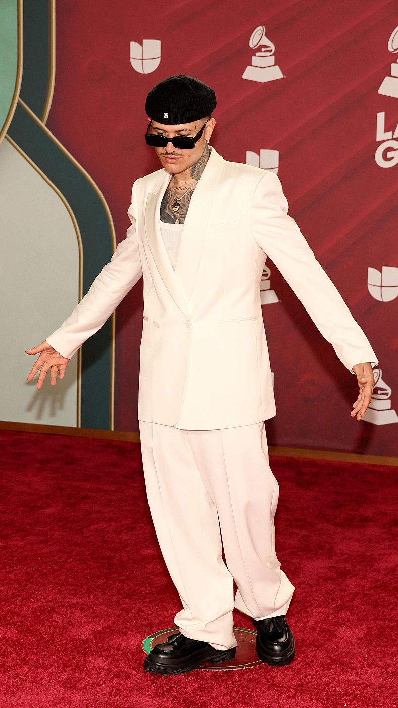 El artista puertorriqueño Kapo posa con un traje blanco en la alfombra roja de los Latin Grammy.