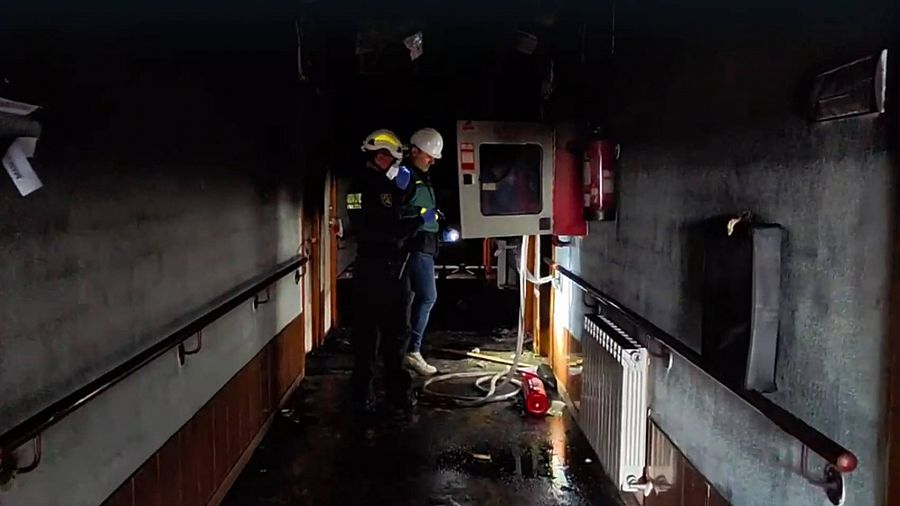 Investigadores de la Guardia Civil en el pasillo de una residencia incendiada en Zaragoza.