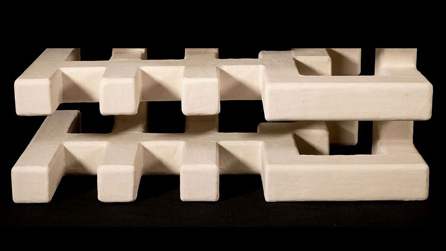 Escultura abstracta de Las Ánimas (Trini Salamanca y Pablo Párraga), con diseño geométrico en beige claro, mostrando una estructura entrelazada en dos niveles.