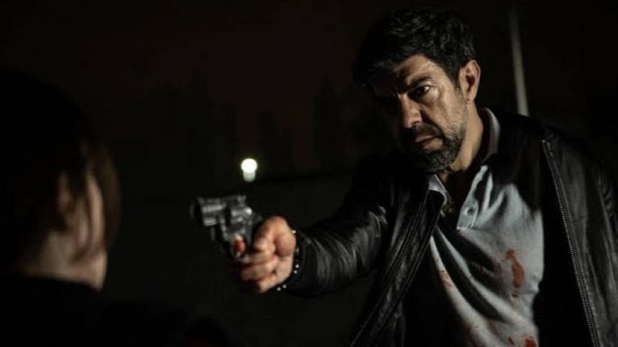 Pierfrancesco Favino apunta con un arma en una oscura escena de 'Última noche en Milán'.