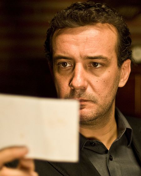 El actor Mario Pastor mira con atención un documento en sus manos.