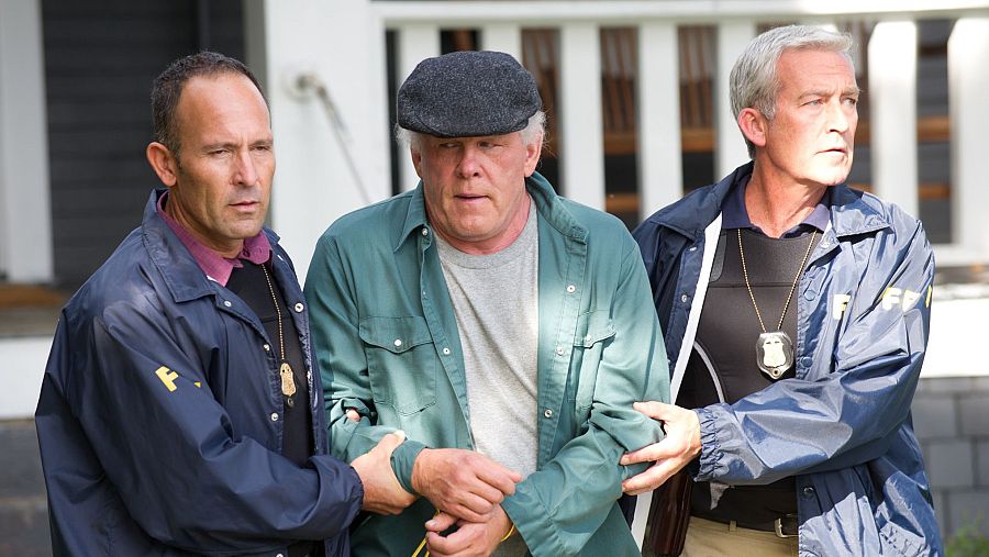 Un hombre es escoltado por dos agentes del FBI con las manos esposadas a la espalda.