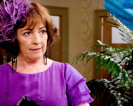 Imagen de Concha Velasco, actriz española, luciendo un vestido morado y tocado de plumas del mismo color.  Velasco mira hacia la derecha de la imagen.
