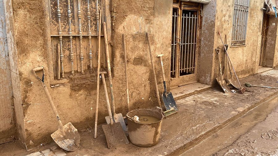 Palas y fregonas cubiertas de barro hacinadas contra una vivienda