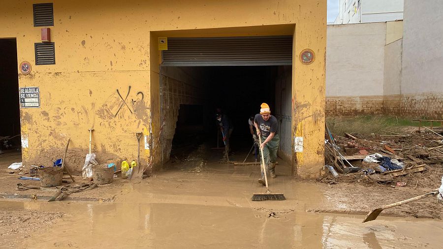 Tres efectivos de los cuerpos de emergencia achican agua de un garaje que ya ha sido revisado