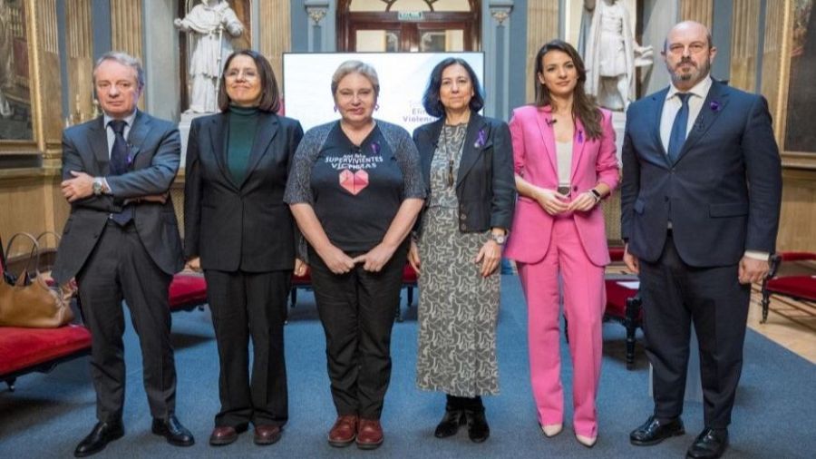 Acto institucional en el Senado español por el Día Internacional de la Eliminación de la Violencia contra la Mujer. Seis personas posan para una foto con lazos morados.
