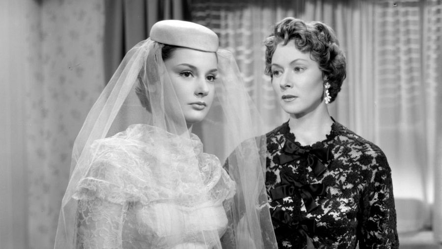 Dos mujeres con vestidos elegantes en una escena en blanco y negro de la película 