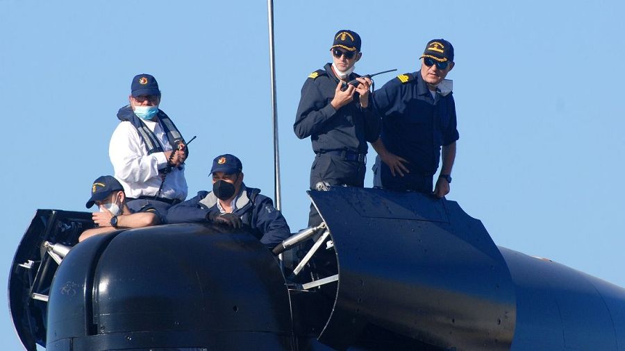 Comandante del submarino S-81 y su tripulación en la torreta. Día despejado, algunos con mascarillas y equipos de comunicación.
