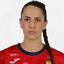 Carmen Campos, jugadora de balonmano española, con camiseta roja y azul (logo Joma), mira a cámara con expresión seria.