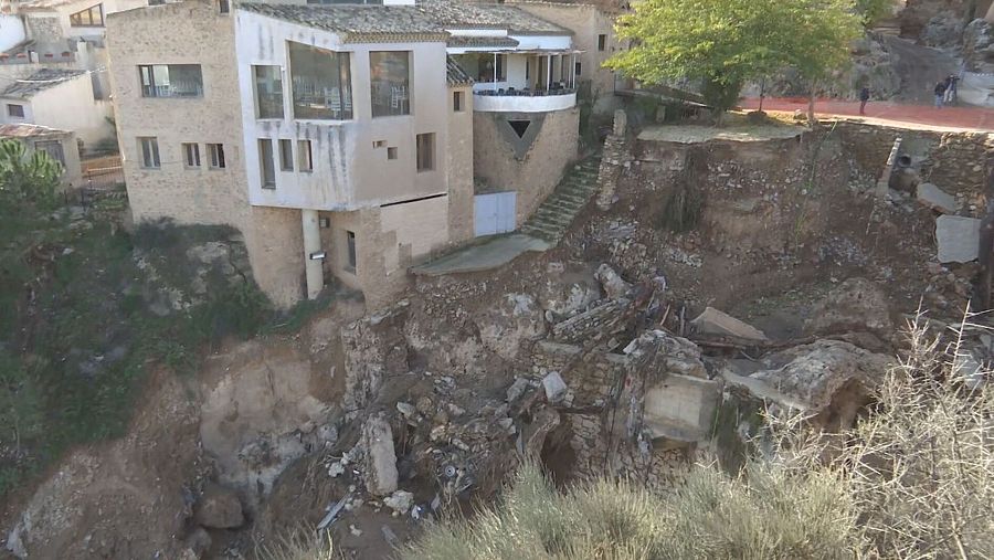 Daños causados por la DANA en Letur, Castilla-La Mancha: edificio afectado por un socavón, personas observando.