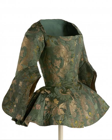 Vestido antiguo verde oscuro con estampado floral, mangas tres cuartos acampanadas y peplum. Prenda exhibida, inspiración para una serie.