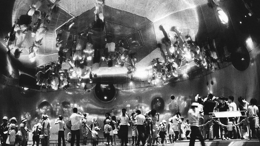 Interior del Pepsi Pavilion en la Expo '70 de Osaka. Domo reflectante mostrando imágenes caleidoscópicas de personas, mayormente familias, observándolo con asombro.