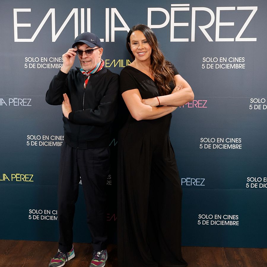 Karla Sofía Gascón y un hombre posan para una foto promocional de la película 'Emilia Pérez'. Fondo azul oscuro con el título de la película y la fecha de estreno: 5 de diciembre.