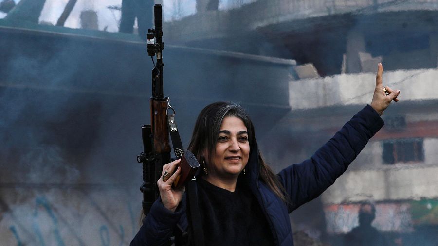 Una mujer armada muestra la V de la victoria mientras los rebeldes celebran la caída de la capital Damasco en manos de los combatientes antigubernamentales