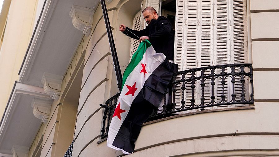 Un manifestante cambia la bandera de la embajada de Siria en Madrid