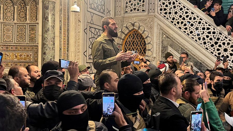 Discurso de un hombre con barba y camisa verde oliva ante una multitud en el interior de una mezquita. Algunos asistentes llevan máscaras y graban con sus móviles.