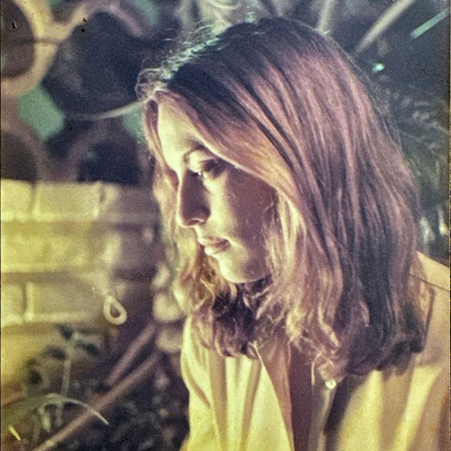 Imagen de portada musical: mujer con cabello castaño claro y ondulado, mirada baja, fondo oscuro y difuminado.