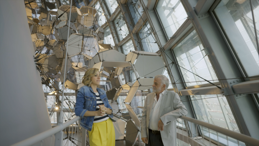 Conversación entre una mujer rubia y un hombre de pelo canoso en un espacio interior moderno con una escultura de metal y cristal.  El texto en catalán destaca la lectura y el sueño para la salud cerebral, incluyendo 'mapas mentales'.