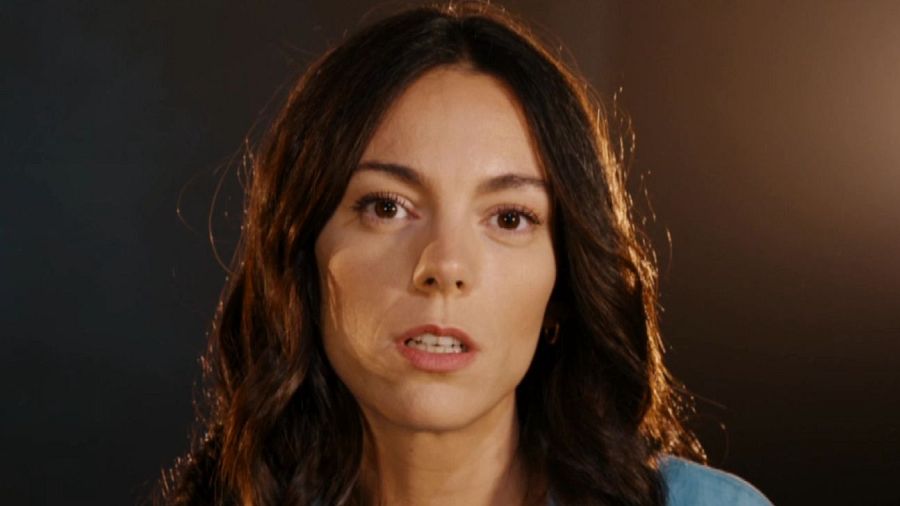 Primer plano de Vicky Luengo, actriz española, con expresión seria y cabello castaño oscuro y ondulado; viste una prenda oscura. Fondo desenfocado.