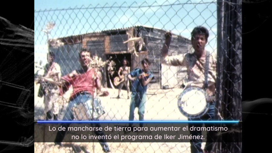 Personas con instrumentos musicales tras una valla en un paisaje polvoriento. Texto superpuesto irónico sobre efectos dramáticos en imágenes. Noticia cultural.