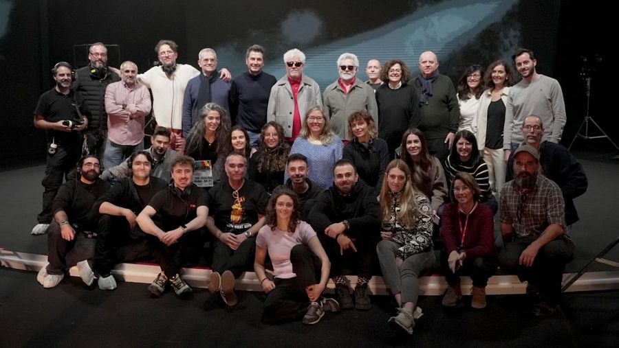 Equipo de rodaje de RTVE posando en estudio de televisión durante la grabación de un programa cultural. Variedad de atuendos y algunos con auriculares.