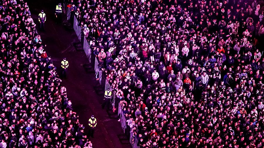 Multitud masiva en celebración de Año Nuevo en Taipei.  Vallas de seguridad y personal con chalecos reflectantes controlan el flujo de personas. Iluminación morada.