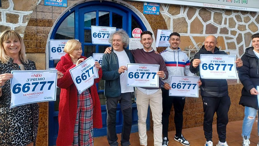 Celebración en Cantabria tras vender el 3º premio (66777) de la Lotería del Niño 2025.  Personas sonrientes muestran carteles anunciando el premio.