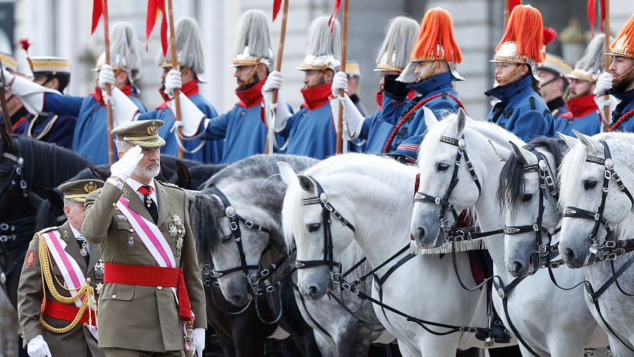 El Rey Felipe VI, en uniforme militar, preside la Pascua Militar 2025, saludando junto a un alto mando militar y la Guardia Real a caballo.
