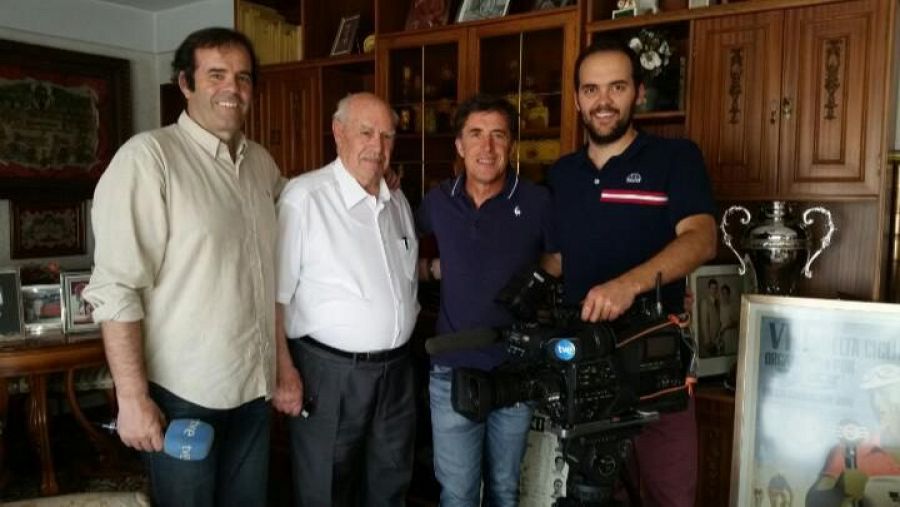 Grabación de un programa de TVE en un ambiente doméstico.  Se ven dos exciclistas, un periodista con micrófono y un cámara.