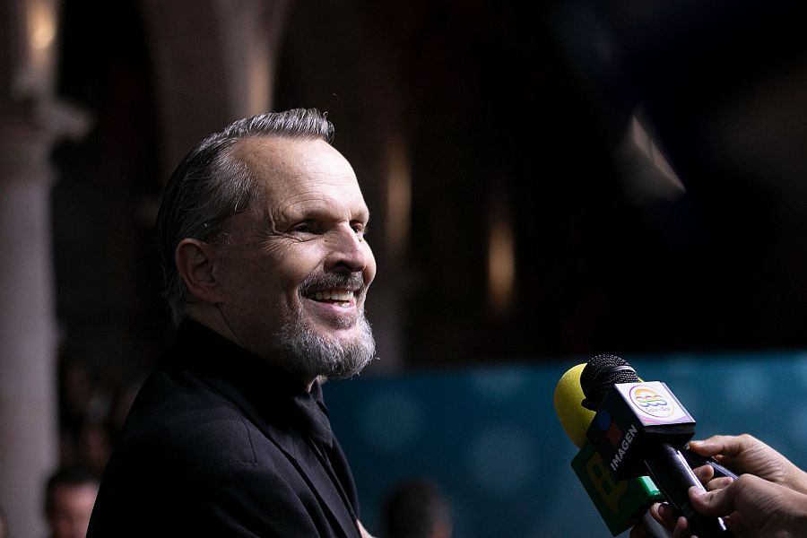 Entrevista a Miguel Bosé con dos micrófonos, uno con la palabra 