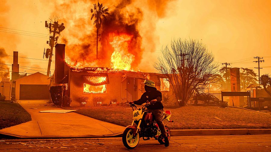 Un motociclista observa una casa en llamas durante el incendio de Eaton