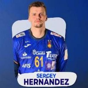 Portero de balonmano con camiseta azul oscuro, número 61 y logos de patrocinadores.  Expresión seria, mirada directa a cámara.