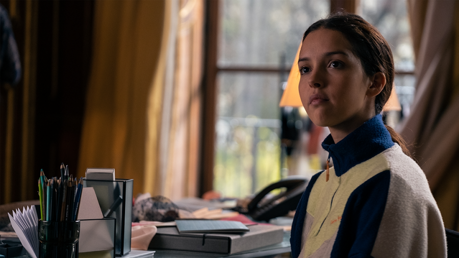 Actriz sentada en un espacio de trabajo con materiales de costura; viste sudadera deportiva y tiene el pelo recogido en coleta.