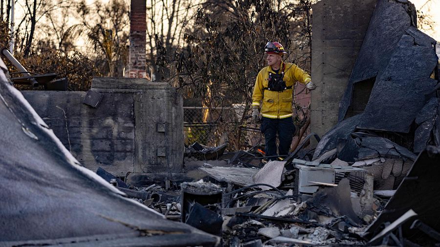 Un bombero camina entre los restos de una casa reducida a escombros por el incendio de Eaton