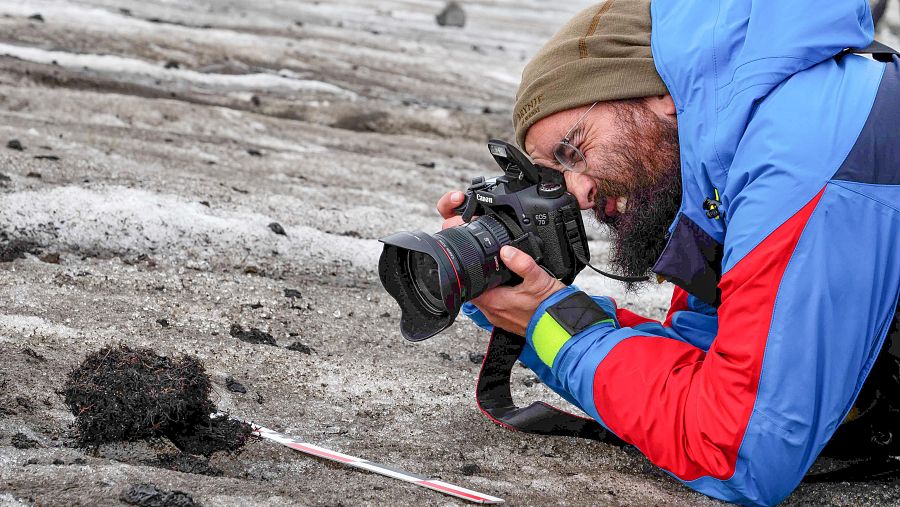 Un arqueólogo fotografiando un hallazgo en el hielo en Lendbreen, Noruega