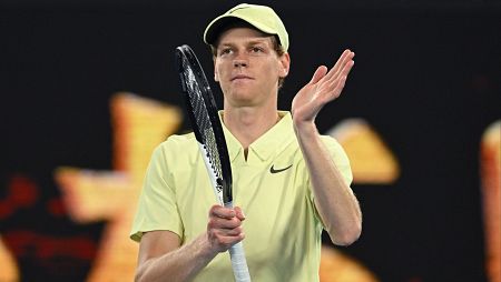 Tenista celebrando una victoria, viste polo amarillo con logo Nike y gorra; expresión de satisfacción.