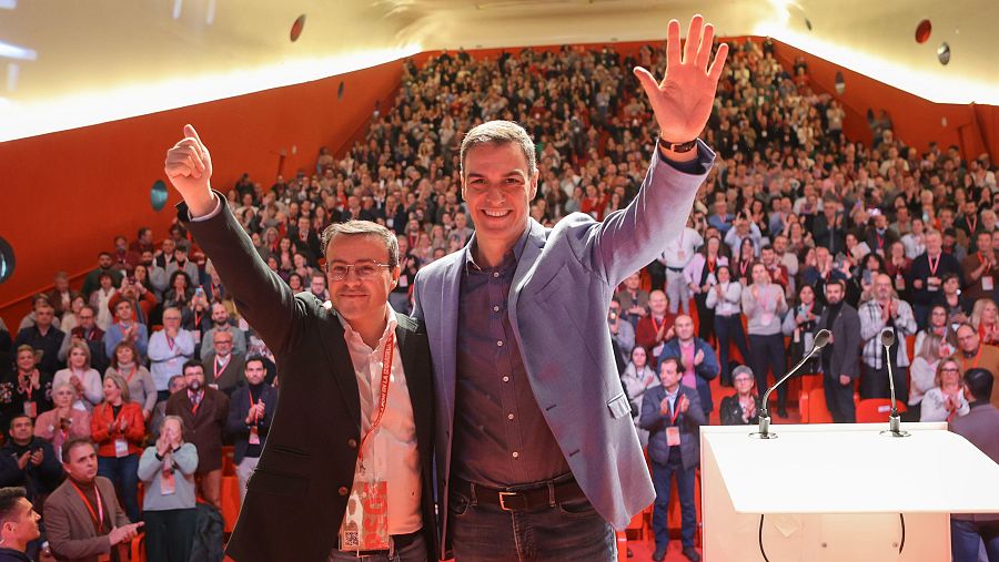 Clausura del XV Congreso del PSOE de Extremadura. Pedro Sánchez, en traje azul, saluda a un auditorio abarrotado que aplaude. Un hombre a su lado levanta el puño.