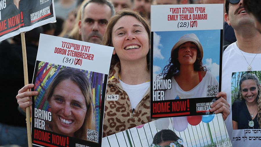 Una mujer porta en Tel Aviv las fotos de dos de las rehenes liberadas