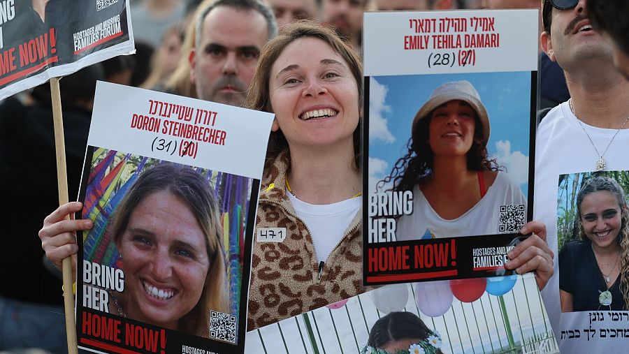 Una mujer porta en Tel Aviv las fotos de dos de las rehenes liberadas