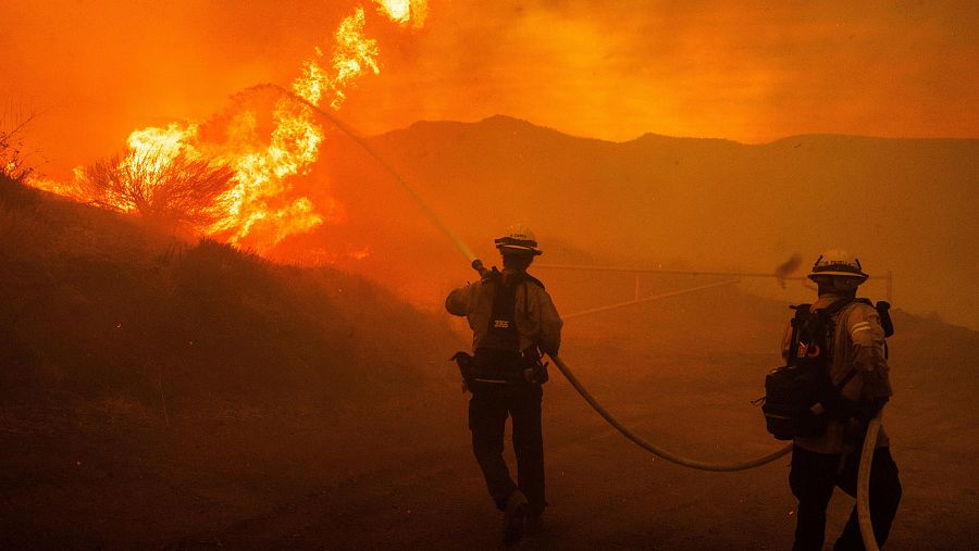 Bomberos rocían agua mientras trabajan en la extinción del incendio Hughes