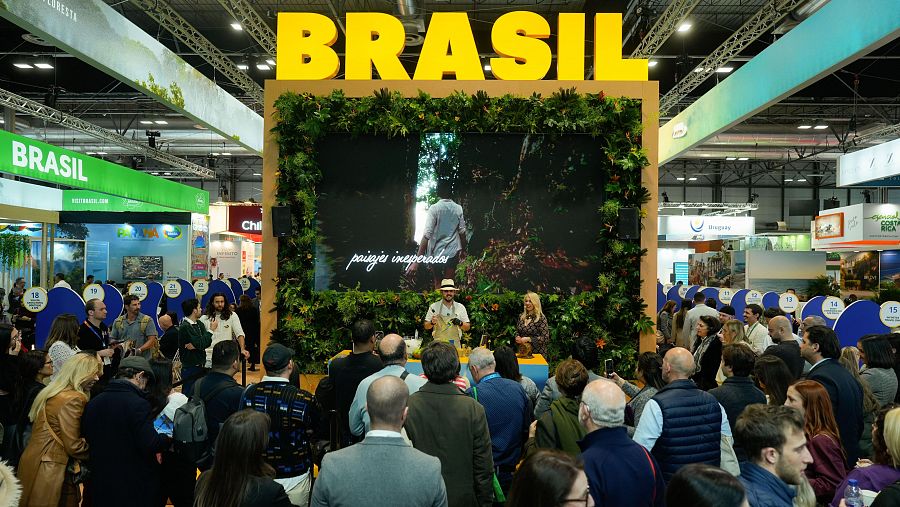 Presentación en Fitur de Brasil: paisajes exuberantes y demostración culinaria con dos presentadores ante numerosa audiencia.